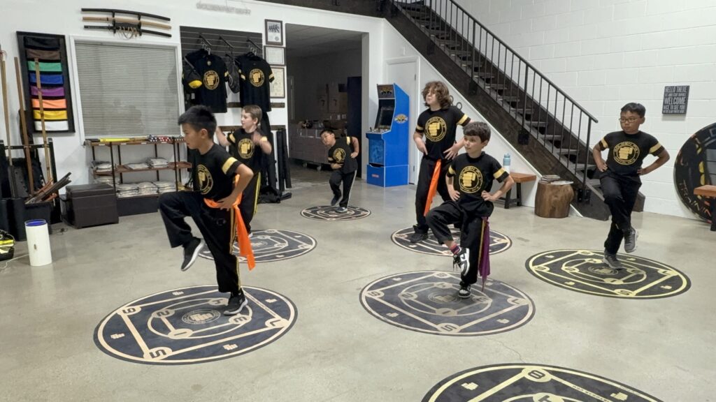 Kids practice balance and coordination with raised knees on Golden Fist Training Circles in Burbank.