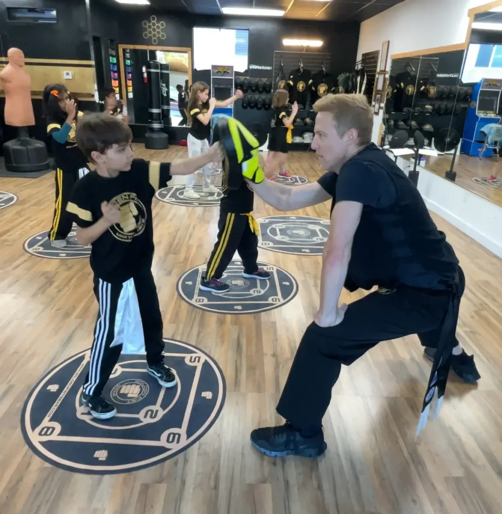 Sifu Jonny Blu holds a focus mitt for a child during a Golden Fist martial arts class.